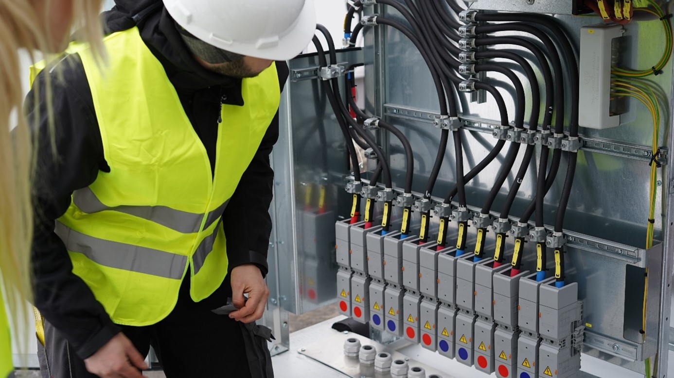 Mitarbeiter der TRICERA energy vor Schaltungen eines Batteriespeichers